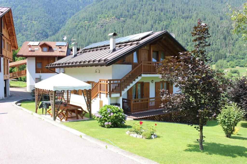 ein Haus mit einem Tisch und einem Sonnenschirm davor in der Unterkunft Villetta Val Di Sole in Commezzadura