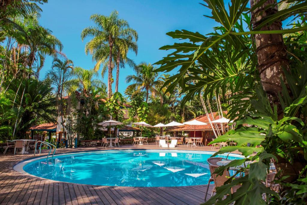 einen Pool in einem Resort mit Palmen in der Unterkunft Hotel Aldeia de Sahy in Barra do Sahy