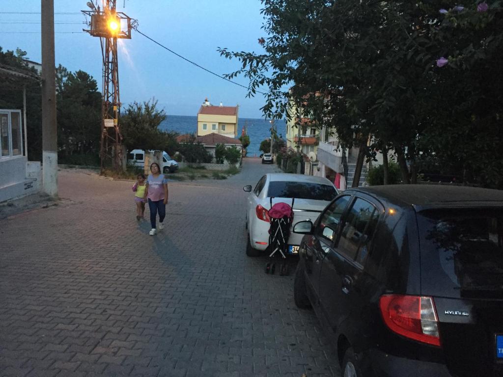 een vrouw en een kind die door een straat lopen met auto's bij Denize 20 adım full eşyalı daire in Tekirdag