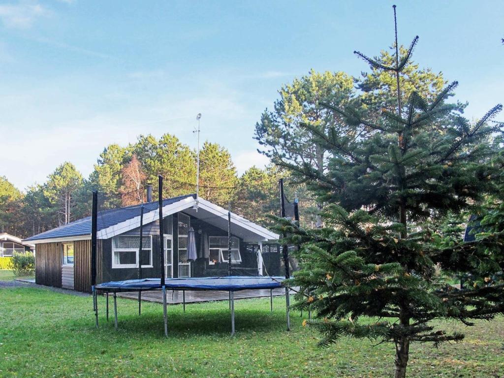 a house with a trampoline in front of a tree at 6 person holiday home in R dby in Rødby