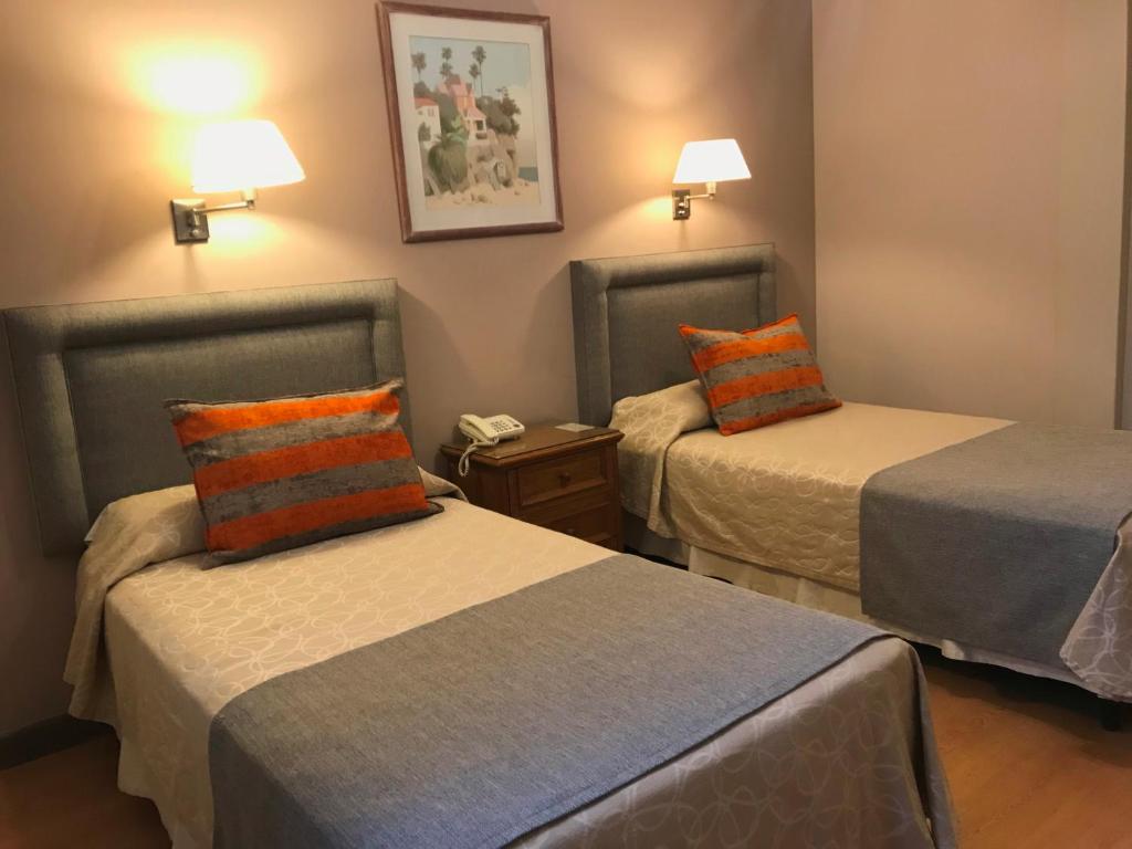 Habitación de hotel con 2 camas y almohadas de color naranja y azul. en Hotel Crillon Mendoza en Mendoza