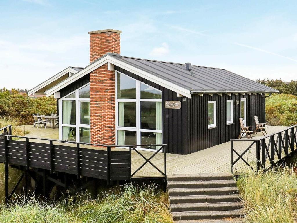 een zwart huis met een terras en een stenen schoorsteen bij 10 person holiday home in L kken in Løkken