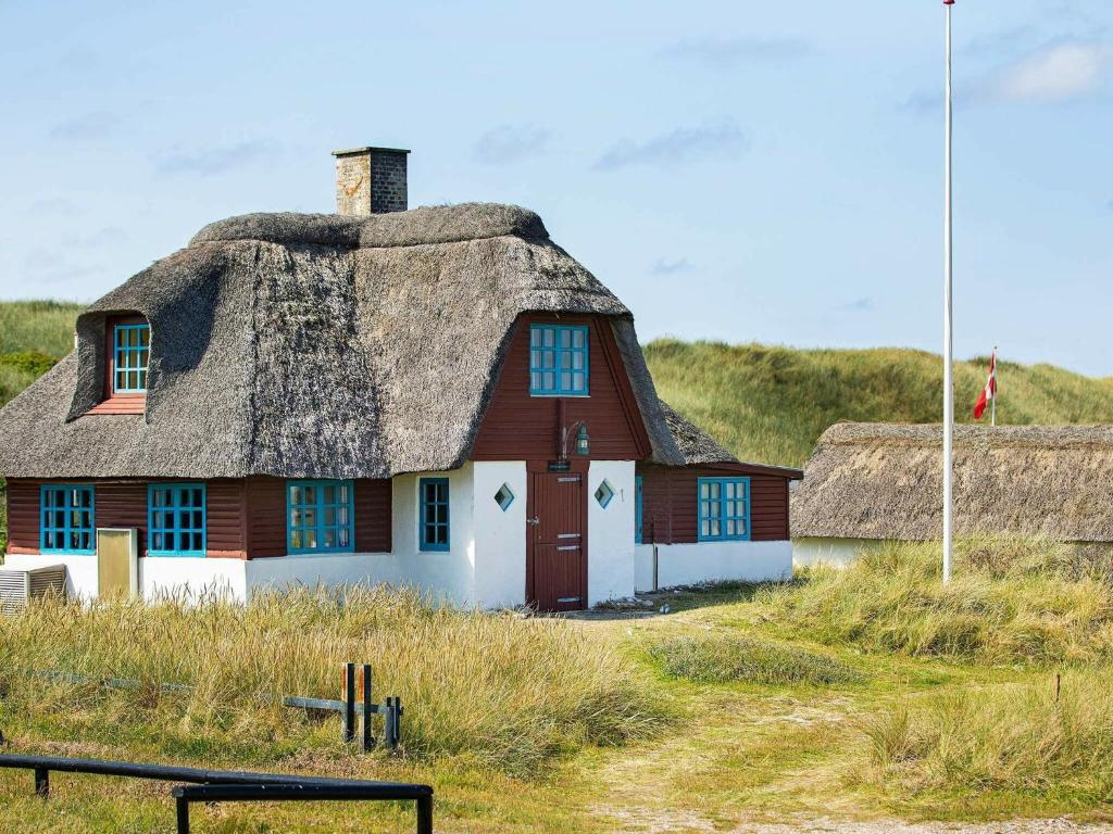 a house with a thatched roof on a beach at 5 person holiday home in Ulfborg in Fjand Gårde