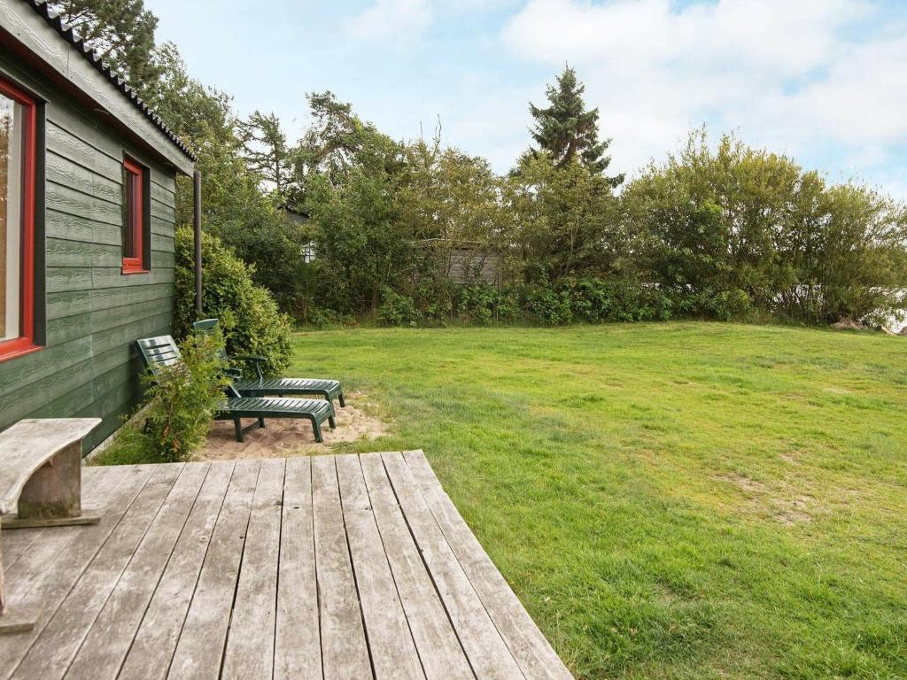 a wooden deck with a bench in a yard at Lakefront Retreat in Sohojlandet - By Traum Ferienwohnungen in Skanderborg