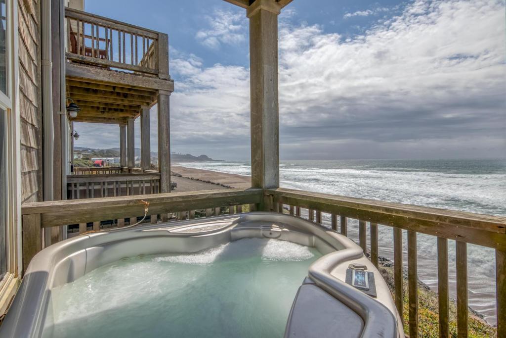 a hot tub on a balcony overlooking the ocean at Looking Glass Inn in Depoe Bay