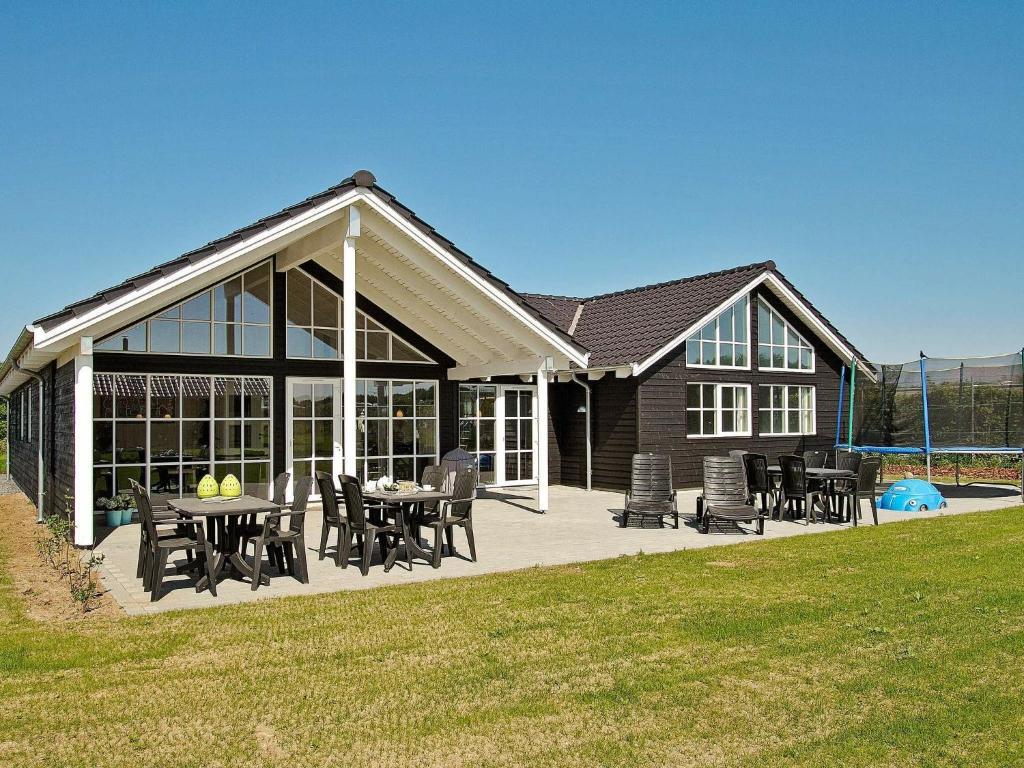 une terrasse avec des tables et des chaises en face d'une maison dans l'établissement 14 person holiday home in Odder, à Odder