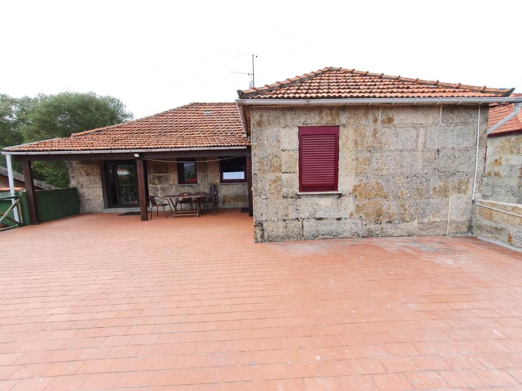 a brick building with a red window and a patio at Casa de Castro Laboreiro in Castro Laboreiro