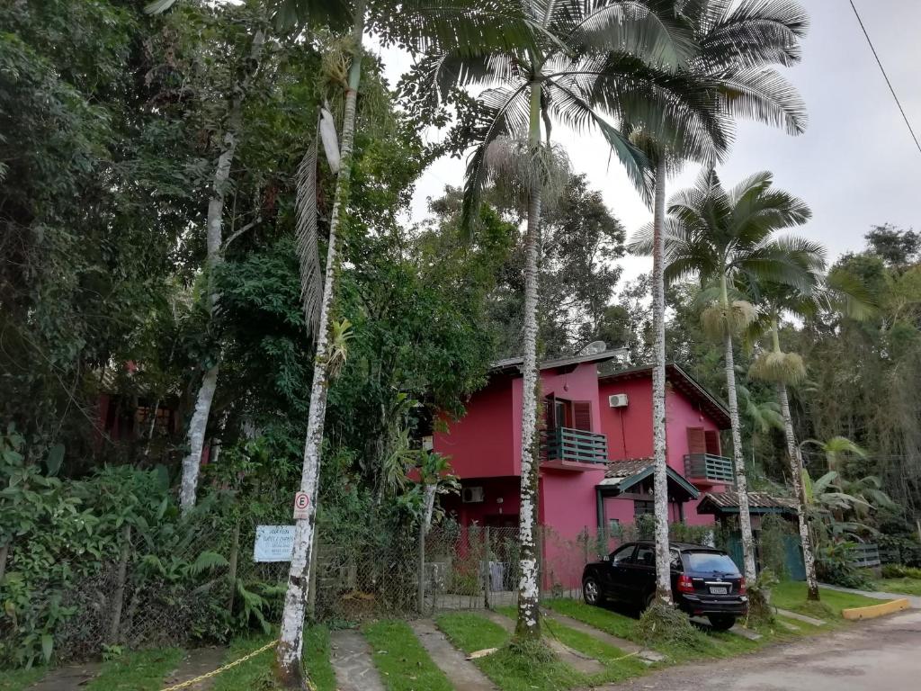 a pink house with a car parked in front of it at Villa Félix Suites e Chalés in Ubatuba