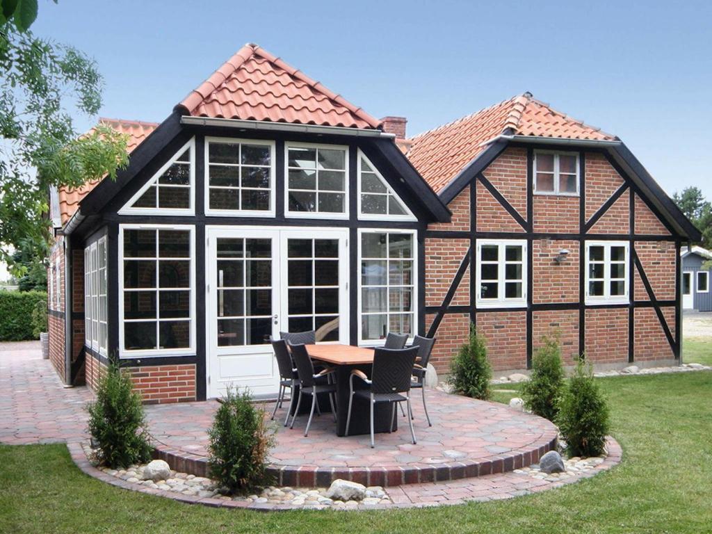 a house with a conservatory with a table and chairs at Four-Bedroom Holiday home in Hemmet 15 in Hemmet