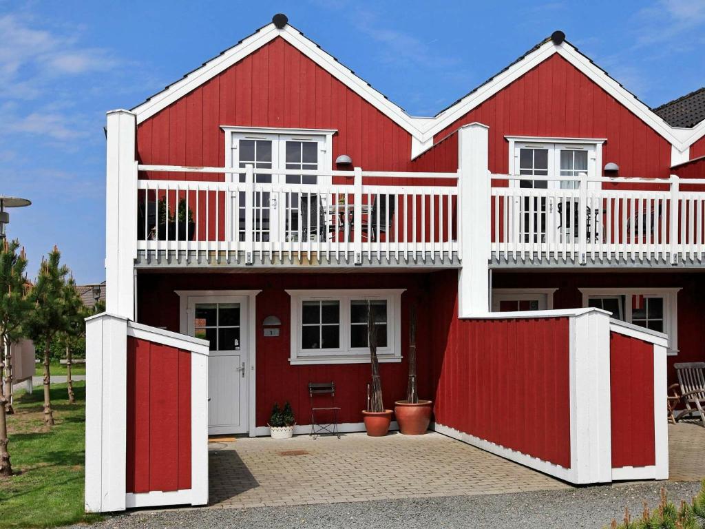 una casa rossa con un balcone bianco sopra di 6 person holiday home in Bl vand a Blåvand