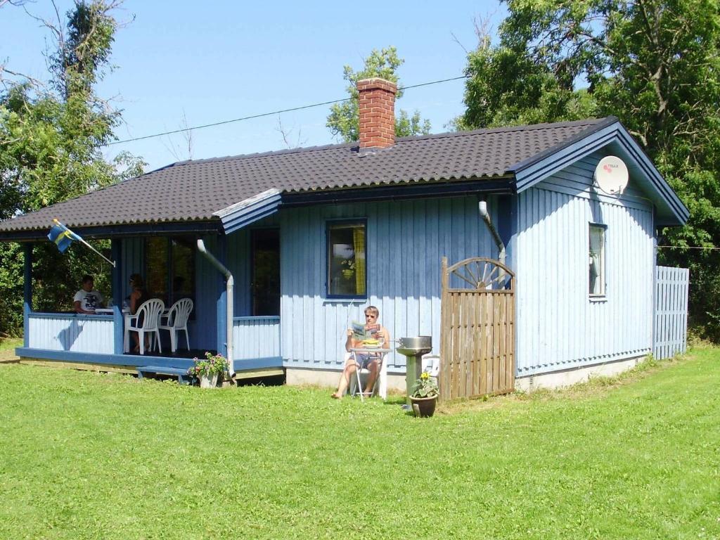 シーピンスリーにある4 person holiday home in K PINGSVIKの小屋の前に座る女
