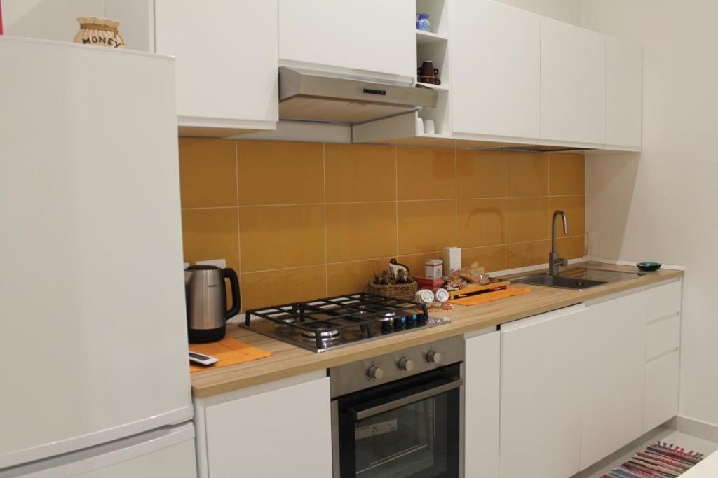 a kitchen with white cabinets and a stove top oven at Le case di Carlotta & Giorgia in Pozzillo