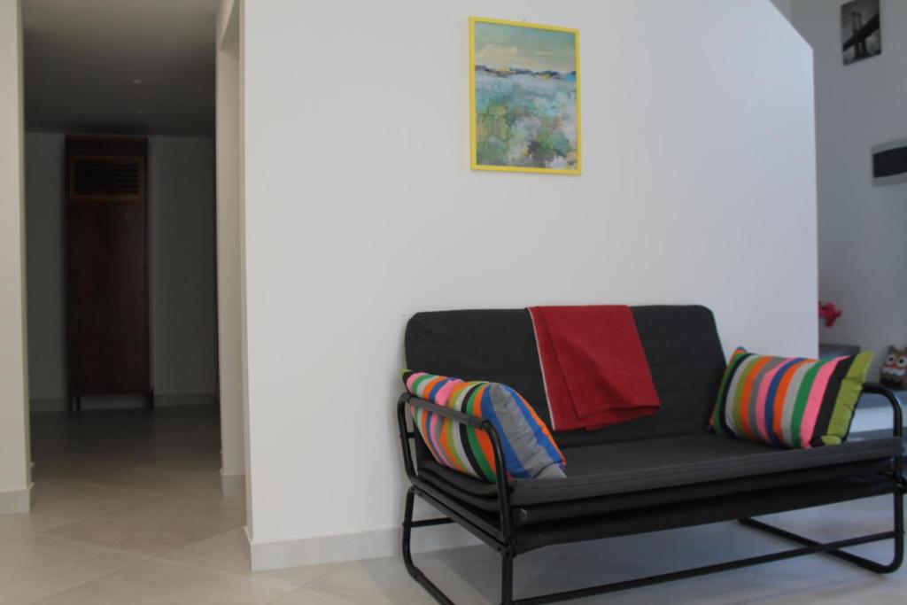 a black bench with colorful pillows on it in a room at Le case di Carlotta & Giorgia in Pozzillo