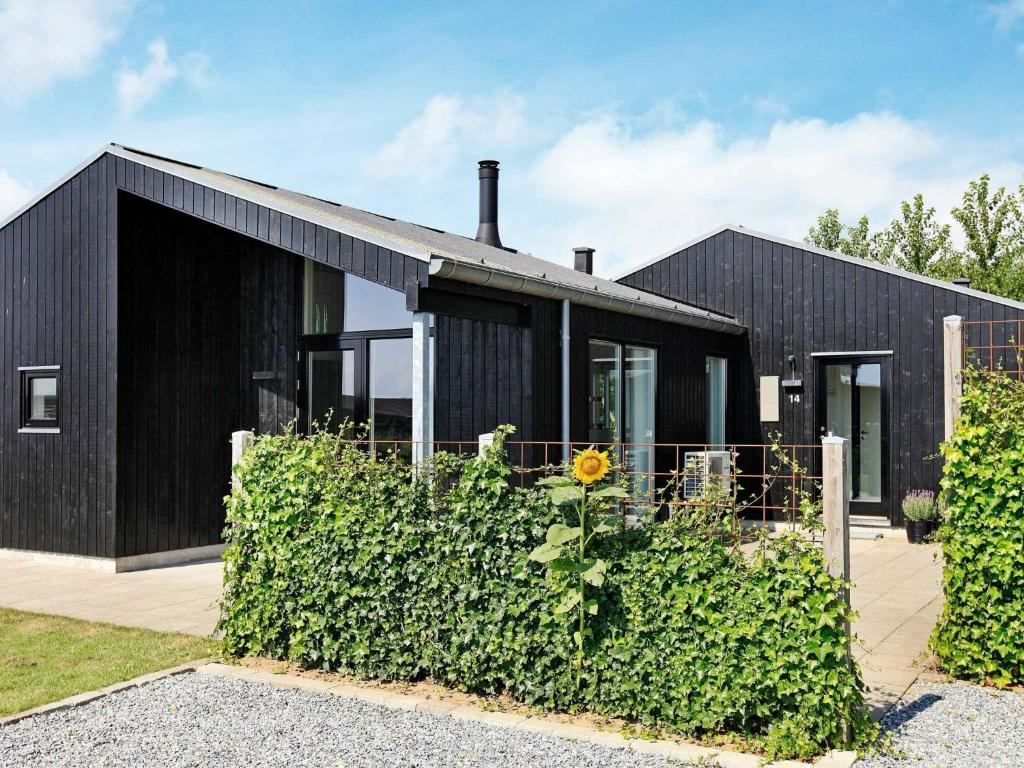 uma casa preta com um girassol à frente. em 8 person holiday home in Haderslev em Årøsund