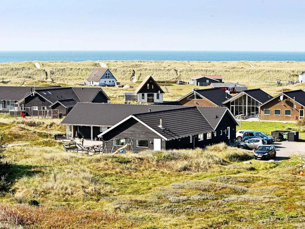 a group of houses on a hill next to the ocean at 22 person holiday home in Harbo re in Harboør