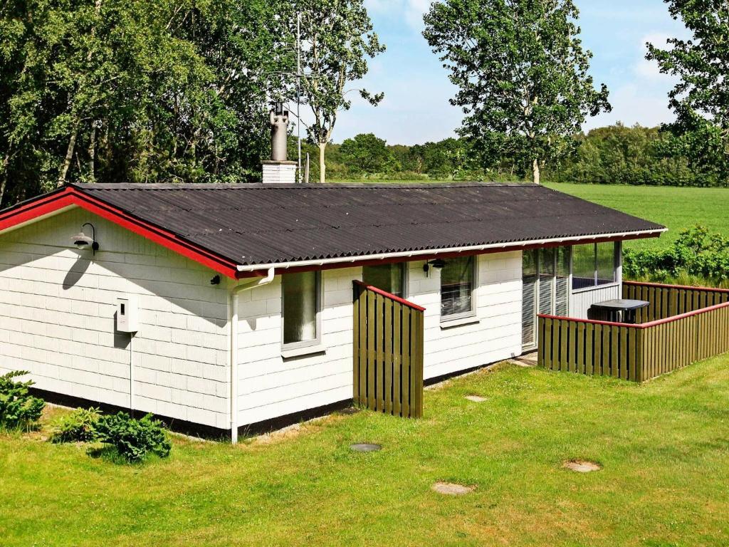 a small white building with a black roof at 4 person holiday home in L s in Læsø