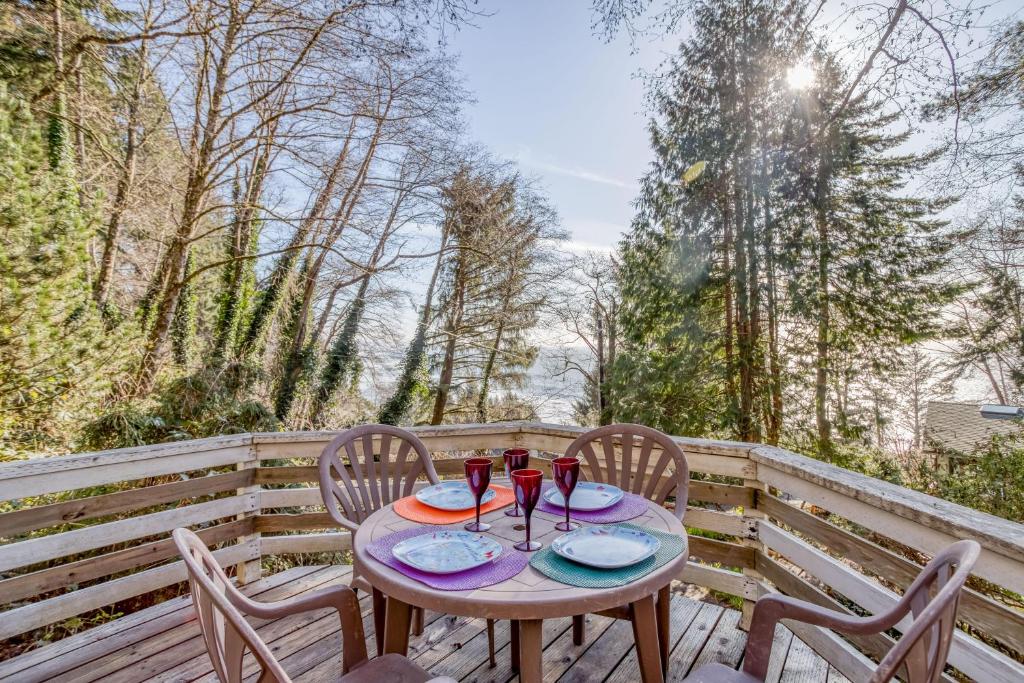 a table with chairs and wine glasses on a deck at 38445 Reed - Meredith Lodging in Manzanita
