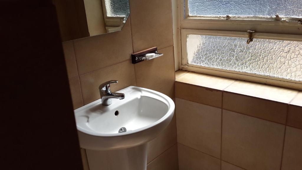 Un baño con lavabo y ventana. en The Shakespeare Inn, en Vanderbijlpark