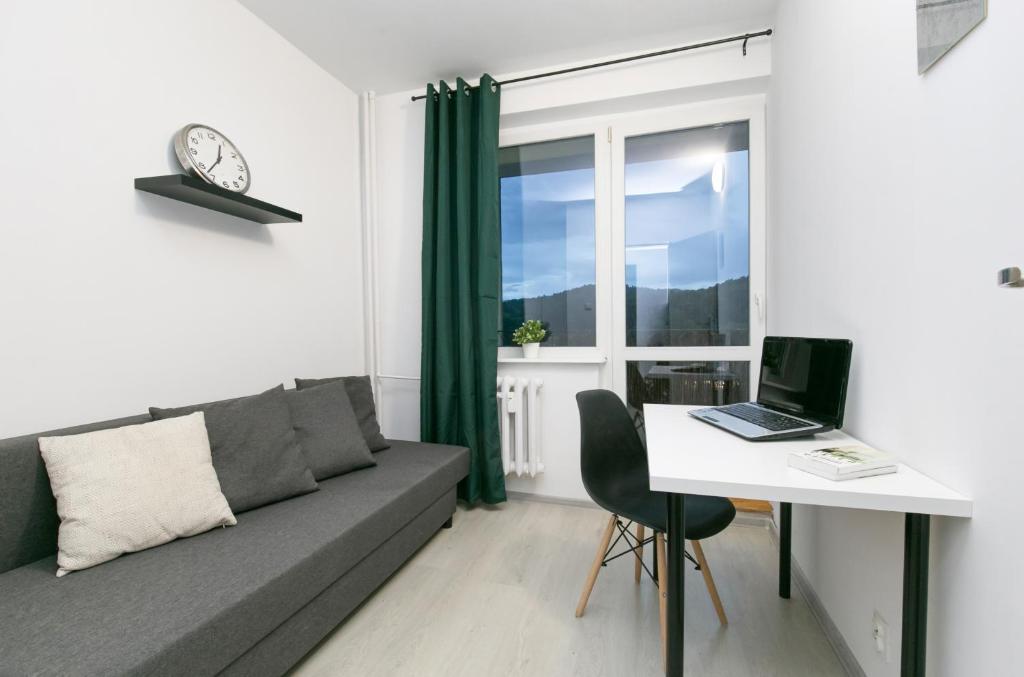 sala de estar con sofá y mesa con ordenador portátil en Rooms4Less en Gdansk
