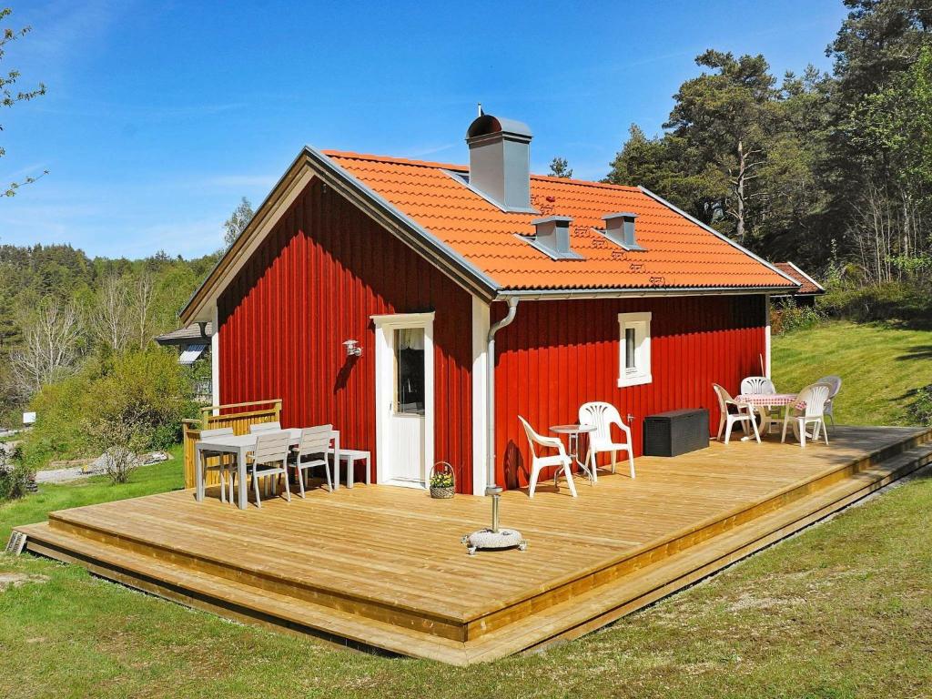 una casa roja con una terraza de madera delante de ella en 4 person holiday home in HEN N, en Nösund