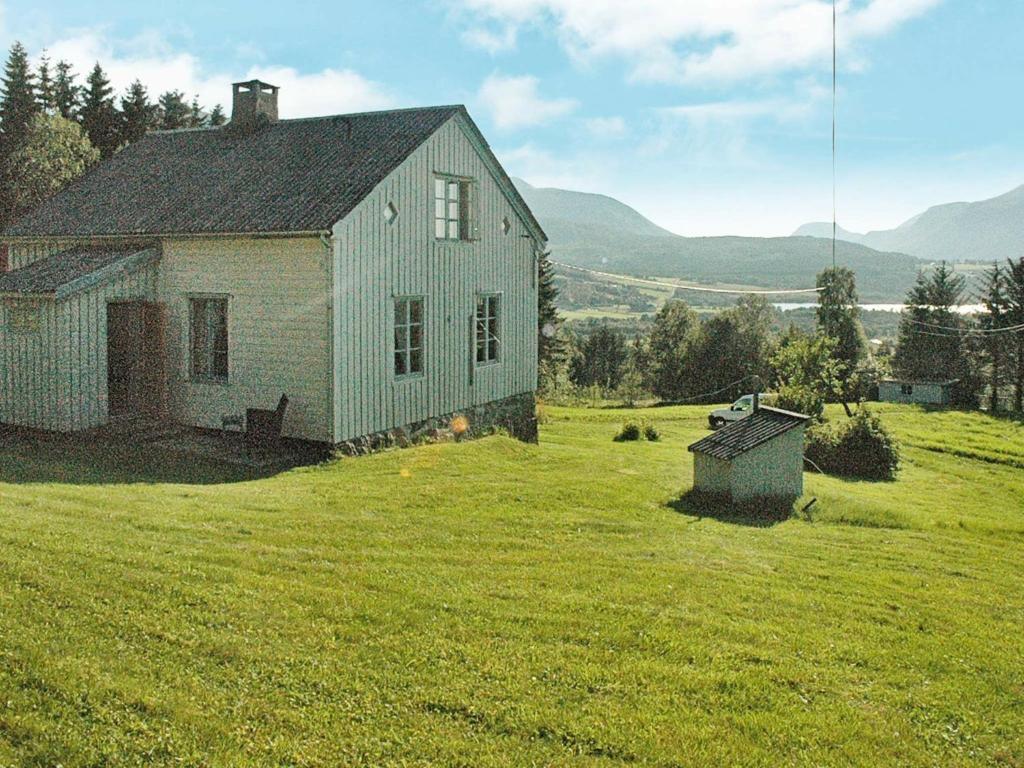 una vieja casa en una colina con césped con un campo en Four-Bedroom Holiday home in Eide, en Eide