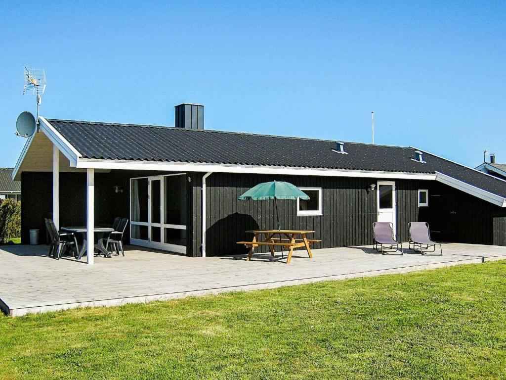 Harboørにある6 person holiday home in Harbo reのパティオ(テーブル、傘付)が備わる家