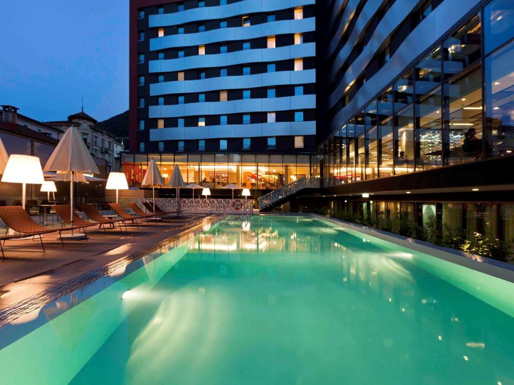 una grande piscina di fronte a un edificio di Novotel Lugano Paradiso a Lugano