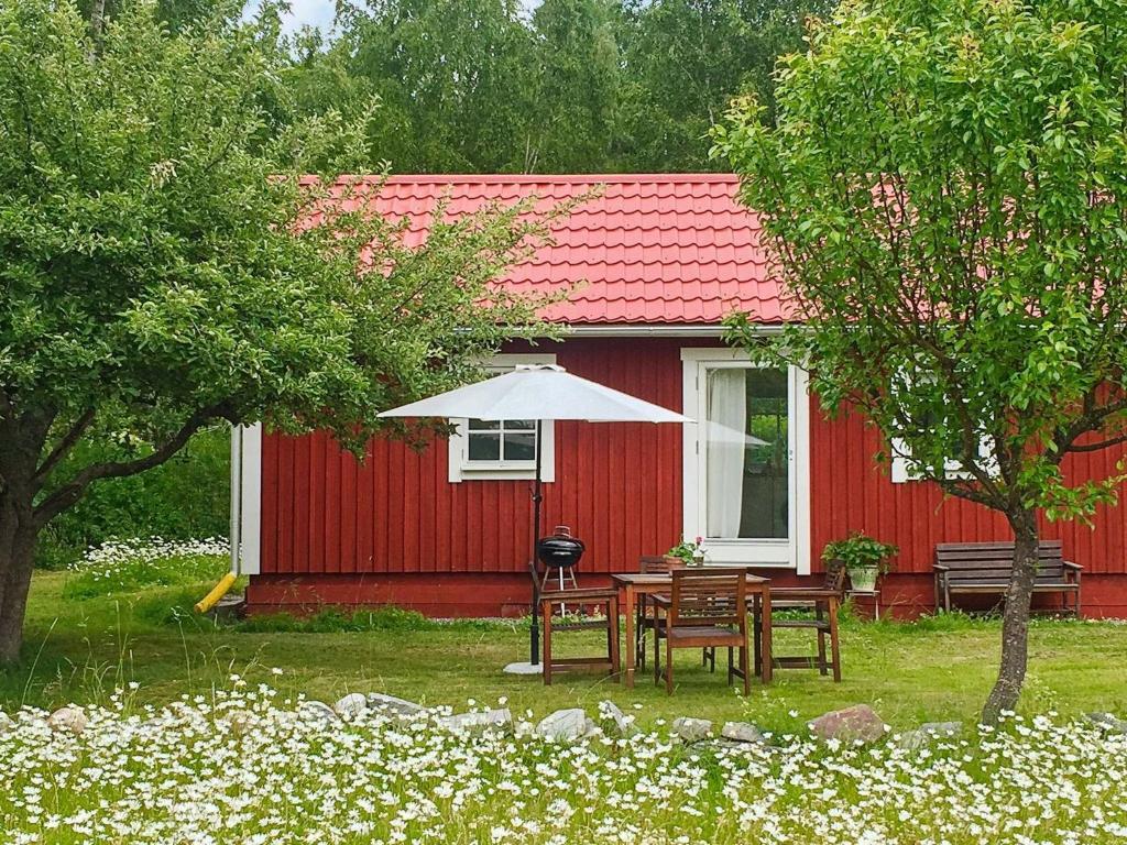 uma casa vermelha com uma mesa e um guarda-chuva em 4 person holiday home in STENHAMRA em Stenhamra