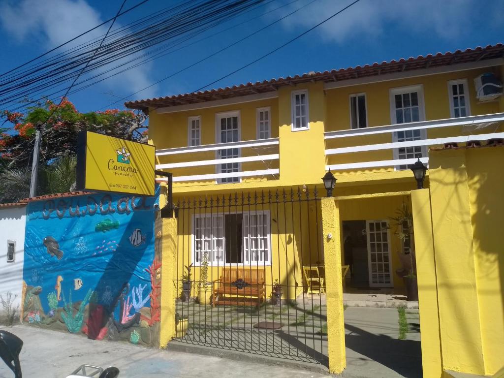 una casa amarilla con un cartel delante en Canema Pousada, en Arraial do Cabo