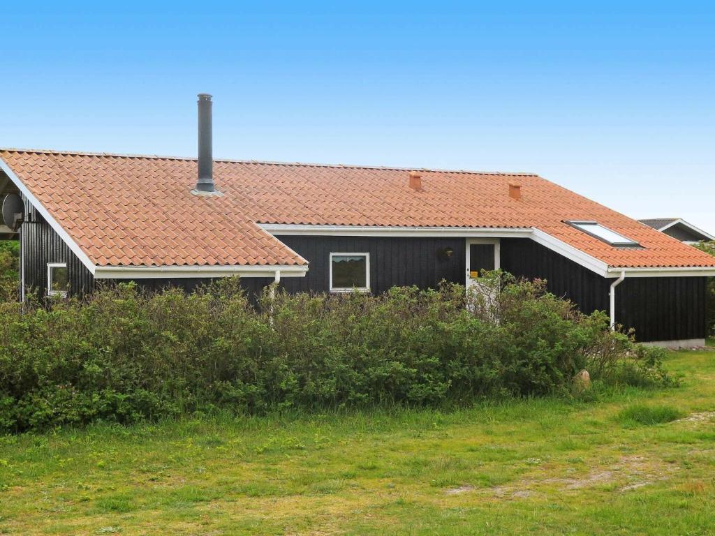een zwart huis met een oranje dak bij 8 person holiday home in Harbo re in Harboør