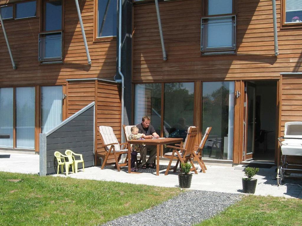 Ein Mann, der vor einem Haus an einem Tisch sitzt. in der Unterkunft 4 person holiday home in Bogense in Bogense