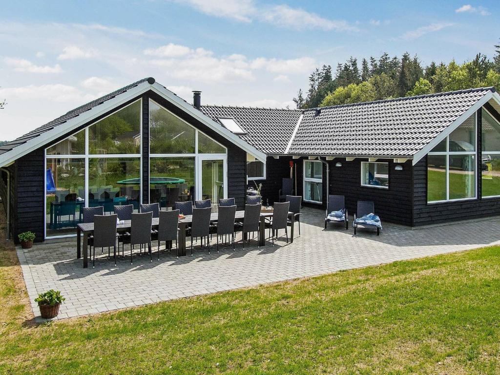 a house with a patio with chairs and windows at 14 person holiday home in Glesborg in Glesborg