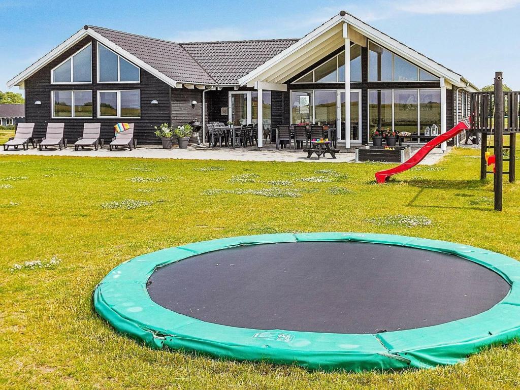 a playground in front of a house with a trampoline at 16 person holiday home in Bogense in Bogense
