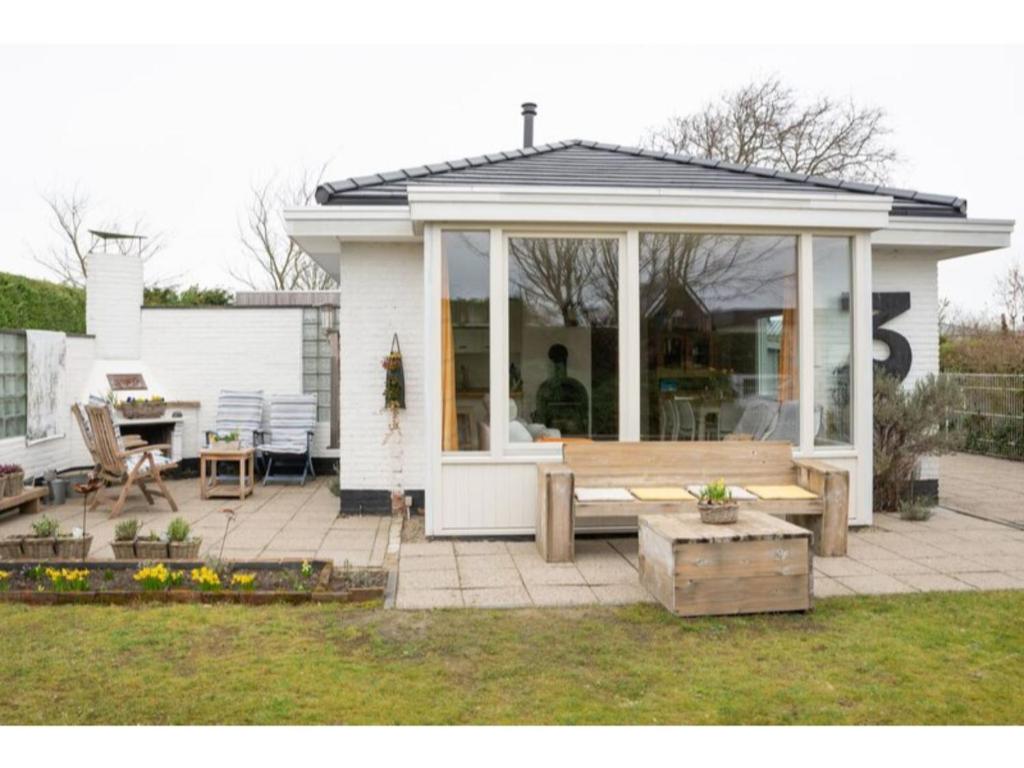 a screened in porch with a table and bench at Quiet location yet close to the beach and center large enclosed garden in Renesse