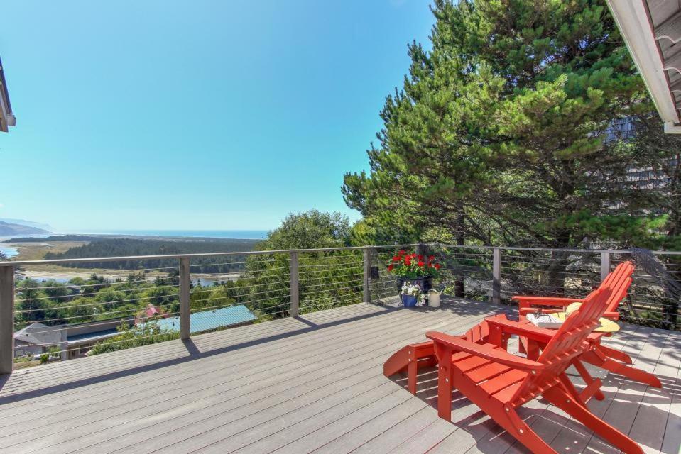 un ponte con due sedie rosse e un tavolo da picnic di Sandpiper Cottage - Meredith Lodging a Pacific City