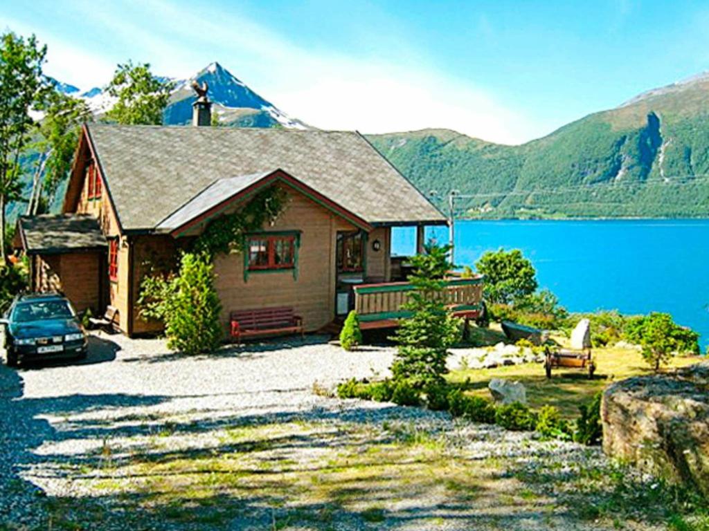 a house with a car parked in front of a lake at Four-Bedroom Holiday home in Hundeidvik in Hundeidvik