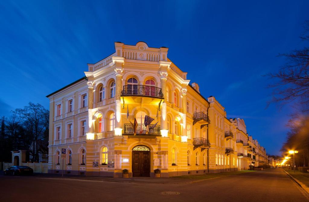 un grand bâtiment jaune avec un balcon dans une rue dans l'établissement Hotel Metropol, à Františkovy Lázně