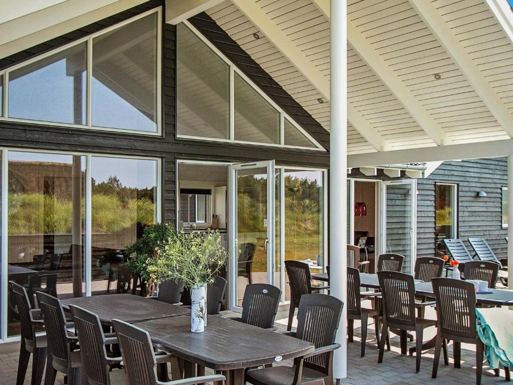 un patio al aire libre con mesas, sillas y ventanas en 18 person holiday home in Bl vand, en Blåvand