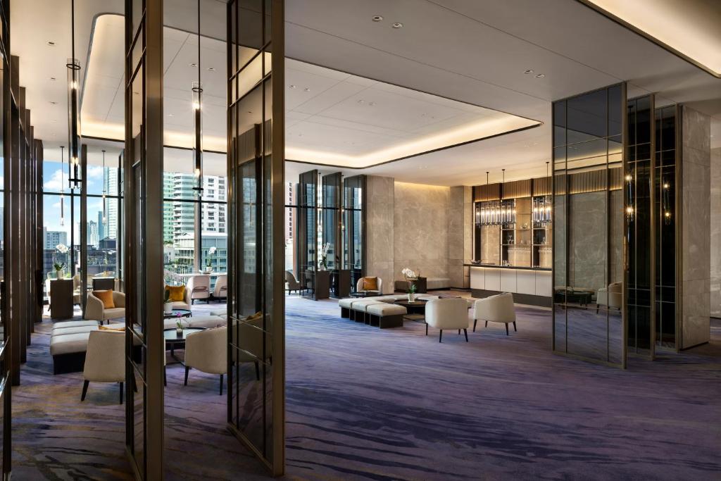 A spacious modern lobby lounge with glass partitions, soft seating, and a city view.