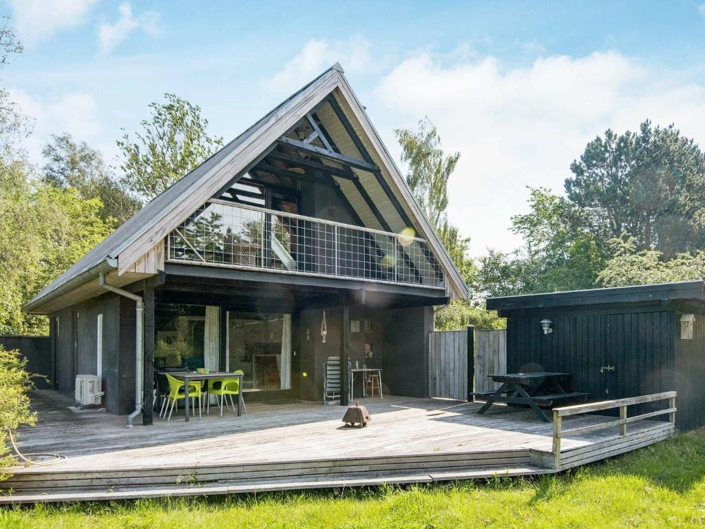 ein Haus mit einem großen Dach auf einer Holzterrasse in der Unterkunft Three-Bedroom Holiday home in Knebel 28 in Skødshoved Strand