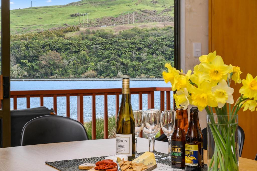 a table with two bottles of wine and yellow flowers at Escape to the Lake - Lake Rotoiti Bach in Okere Falls
