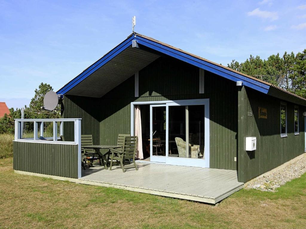 ein grünes Gebäude mit einer Terrasse und einem Tisch in der Unterkunft 6 person holiday home in Ringk bing in Ringkøbing