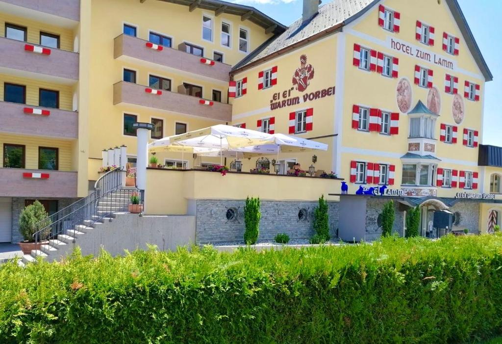 ein großes gelbes Gebäude mit einem Restaurant davor in der Unterkunft Hotel zum Lamm in Tarrenz