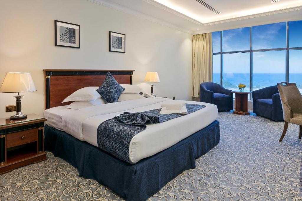 a hotel room with a large bed and a large window at Crown Tower Hotel in Al Jubail