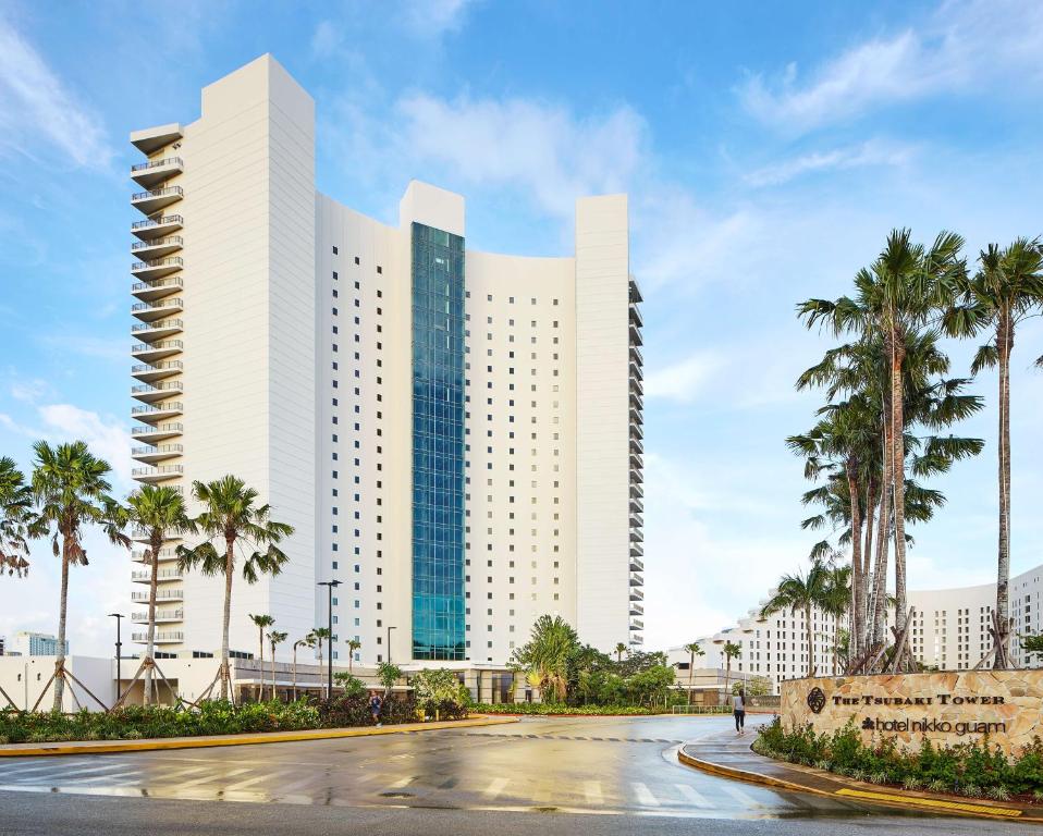 a large white building with palm trees in front of it at The Tsubaki Tower in Tumon