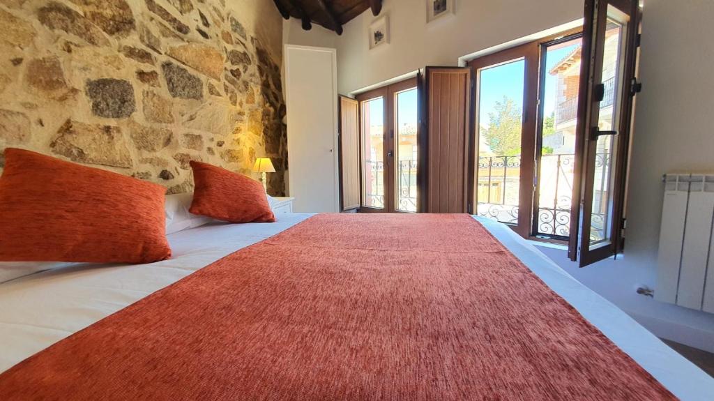 a bedroom with a large bed with a red rug on it at Casas del Castillo, 3 in Ávila