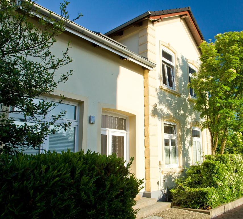 une maison blanche avec des buissons devant elle dans l'établissement Skerra Apartments "am Fitness-Studio", à Fehmarn