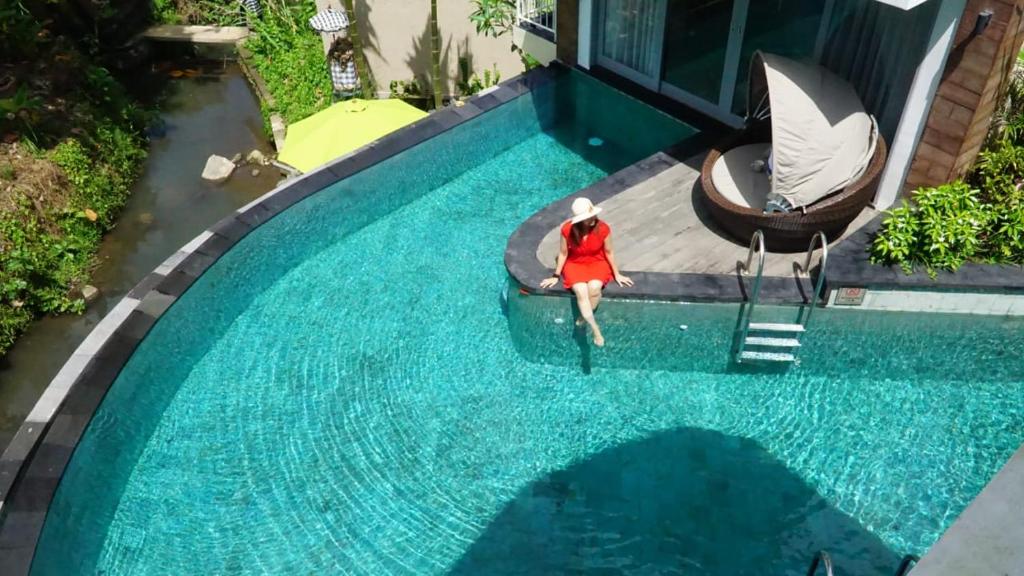 une femme en tenue rouge se tient debout dans une piscine dans l'établissement Tanamas Villas Ubud by Best Deals Asia Hospitality, à Ubud