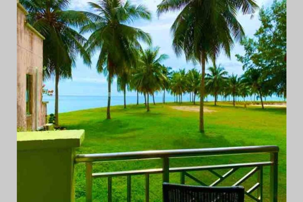 uma varanda com vista para uma praia com palmeiras em Port Dickson PD Malacca Straits Homestay em Porto Dickson
