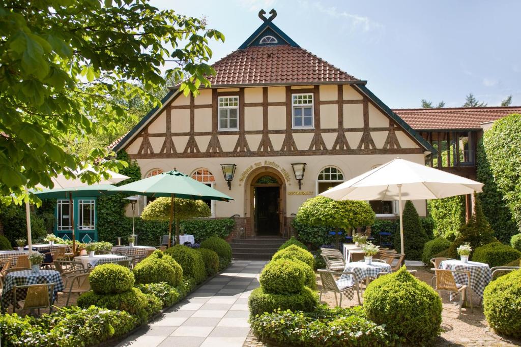a building with tables and umbrellas in front of it at Hotel zur Kloster-Mühle in Groß Meckelsen